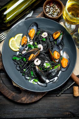 Akdeniz yemekleri. Spagetti mürekkep balığı mürekkep, istiridye ve beyaz şarap. Ahşap bir arka plan üzerinde.