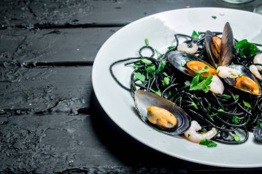 Akdeniz yemekleri. Mürekkep balığı mürekkep ve istiridye spagetti. Rustik siyah arka plan üzerine.