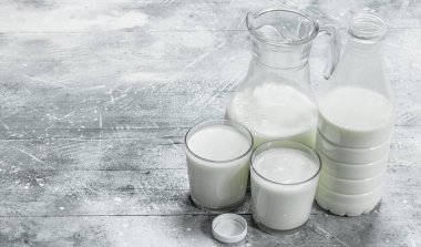 Bir sürahi ve bardak taze süt. Rustik bir arka plan üzerinde .