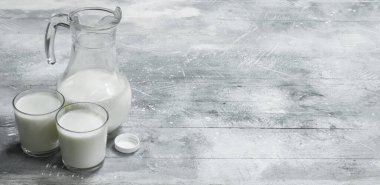 Bir sürahi ve bardak taze süt. Rustik bir arka plan üzerinde .