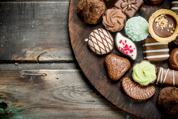 stock image Chocolate sweets on a wooden Board. On a wooden background.