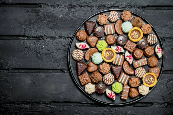 Chocolates on the tray. On black rustic background.