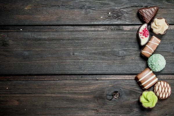 Chocolate sweets with nuts and various fillings. On a wooden background.