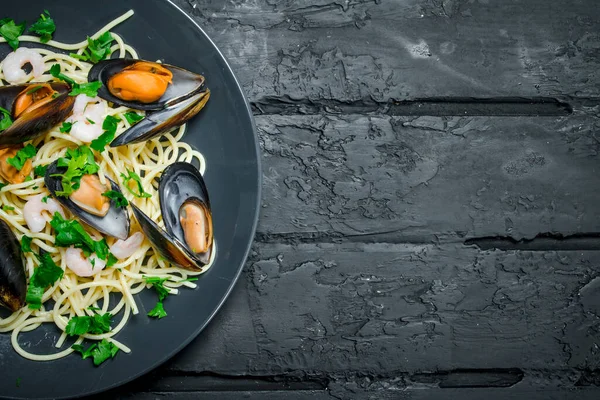 Akdeniz yemekleri. Deniz ürünleri istiridye spagetti. Siyah bir rustik arka planda.