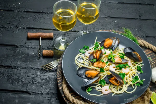 Akdeniz yemekleri. Deniz mahsulleri spagetti istiridye ve beyaz şarap. Siyah bir rustik arka planda.