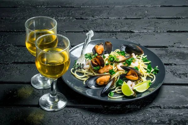 Akdeniz yemekleri. Deniz mahsulleri spagetti istiridye ve beyaz şarap. Siyah bir rustik arka planda.