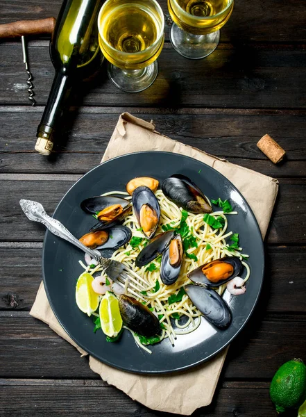 Akdeniz yemekleri. Deniz mahsulleri spagetti istiridye ve beyaz şarap. Ahşap bir arka plan üzerinde.