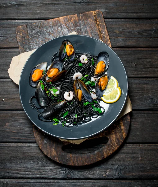 stock image Mediterranean food. Spaghetti with cuttlefish black ink and clams. On a wooden background.