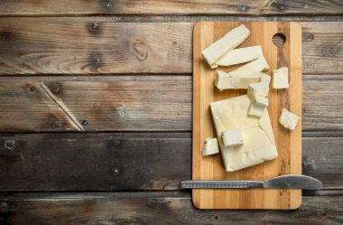 Gemide bir bıçakla tereyağı. Ahşap bir arka plan üzerinde.