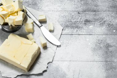 Bir kase içinde bir bıçak ile tereyağı. Rustik bir arka plan üzerinde.