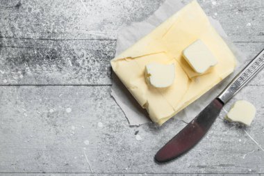 Bıçakla kağıt üzerinde tereyağı. Rustik bir arka plan üzerinde.