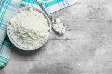 Peçete üzerinde kase süzme peynir. Rustik bir arka plan üzerinde.