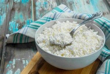 Peçete üzerinde kase süzme peynir. Rustik bir arka plan üzerinde.