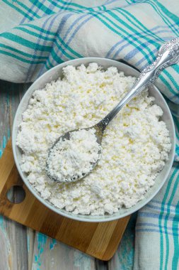 Peçete üzerinde kase süzme peynir. Rustik bir arka plan üzerinde.