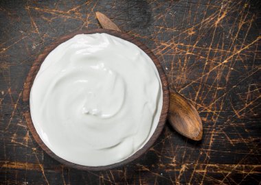 Kase kaşık taze krema. Ahşap bir arka plan üzerinde.