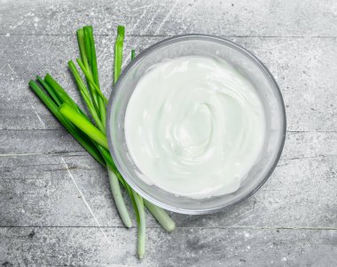 Ekşi krema kase yeşil soğan ile. Rustik bir arka plan üzerinde.