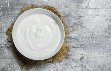 Ekşi krema kase. Rustik bir arka plan üzerinde.