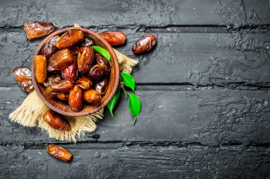 Tarihleri ile yeşil yaprakları ile bir kase. Rustik siyah arka plan üzerine.