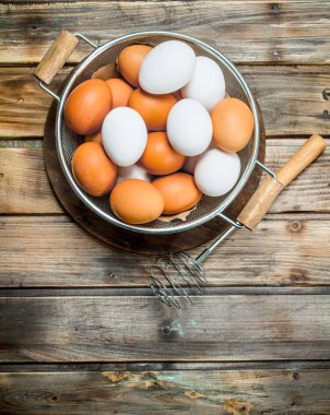 Bir çırpma teli ile bir tencerede yumurta. Ahşap bir arka plan üzerinde.