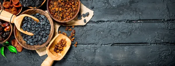 stock image Raisins in a bowl with a scoop. On black rustic background.