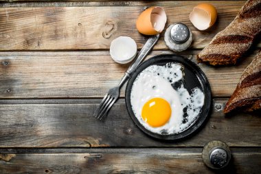Çavdar ekmeği ile bir tavada kızarmış yumurta. Ahşap bir arka plan üzerinde.
