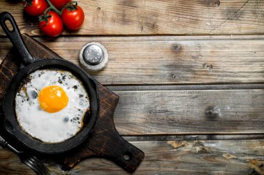 Domates ile bir tavada kızarmış yumurta. Ahşap bir arka plan üzerinde.