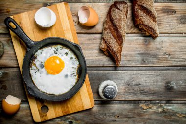 Çavdar ekmeği ile bir tavada kızarmış yumurta. Ahşap bir arka plan üzerinde.