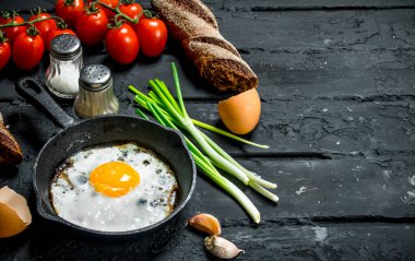 Sahanda yumurta ekmek ve domates ile bir tavada. Rustik siyah arka plan üzerine.