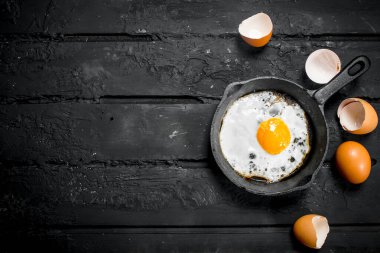 Bir tavada kızarmış yumurta. Rustik siyah arka plan üzerine.