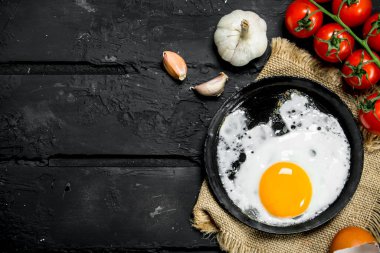 Sarımsak ve domates ile kızarmış yumurta. Siyah rustik arka plan üzerinde
