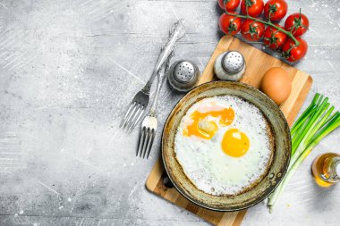 Domates ve yeşil soğan ile bir tavada kızarmış yumurta. Rustik bir arka plan üzerinde.