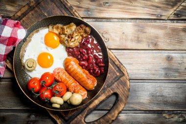 İngiliz kahvaltısı. Kızarmış yumurta sosis, pastırma ve kırmızı fasulye konserve. Ahşap bir arka plan üzerinde.