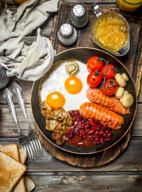 İngiliz kahvaltısı. Kızarmış yumurta sosis, pastırma ve kırmızı fasulye konserve. Ahşap bir arka plan üzerinde.