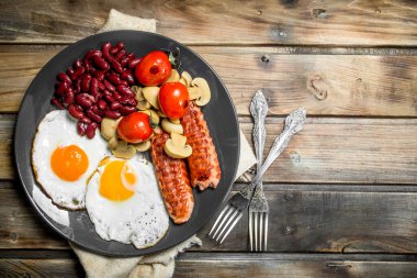 İngiliz kahvaltısı. Kızarmış yumurta sosis, mantar ve fasulye. Ahşap bir arka plan üzerinde.