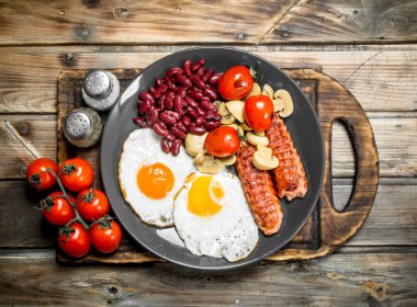 İngiliz kahvaltısı. Kızarmış yumurta sosis, mantar ve fasulye. Ahşap bir arka plan üzerinde.