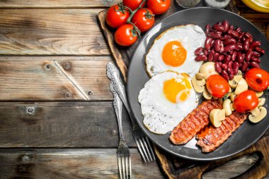 İngiliz kahvaltısı. Kızarmış yumurta sosis, mantar ve fasulye. Ahşap bir arka plan üzerinde.