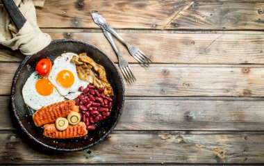 İngiliz kahvaltısı. Kızarmış yumurta sosis, mantar ve fasulye. Ahşap bir arka plan üzerinde.