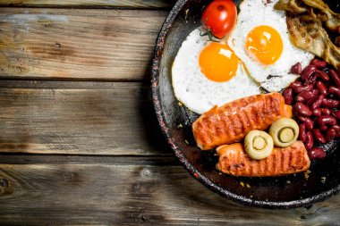 İngiliz kahvaltısı. Kızarmış yumurta domates, sosis ve fasulye. Ahşap bir arka plan üzerinde.