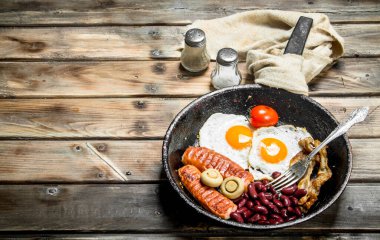 İngiliz kahvaltısı. Kızarmış yumurta domates, sosis ve fasulye. Ahşap bir arka plan üzerinde.