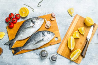 Çiğ deniz balık dorado domates, limon dilimleri ve baharatlar ile. Rustik bir arka plan üzerinde.