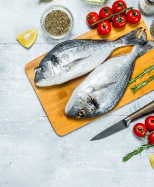 Çiğ deniz balık dorado baharat ve domates ile. Rustik bir arka plan üzerinde.