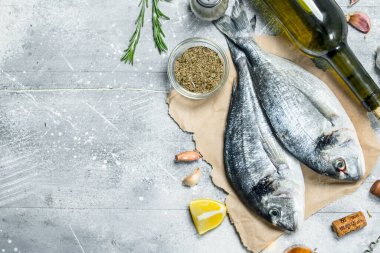 Çiğ deniz dorado beyaz şarap ile balık ve baharat. Rustik bir arka plan üzerinde.