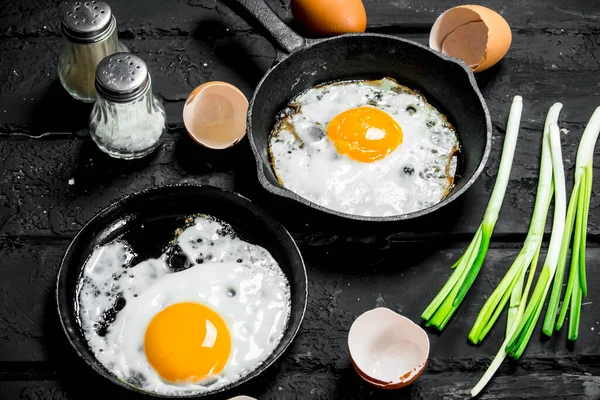 stock image Fried egg with green onions and seasonings. On black rustic background.