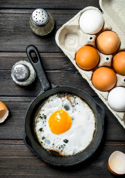 stock image Fried egg in a frying pan. On a wooden background.