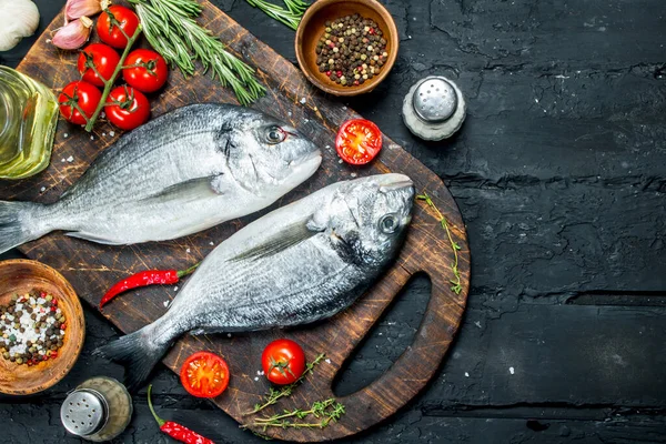 stock image Raw sea fish dorado with spices and rosemary. On a black rustic background.