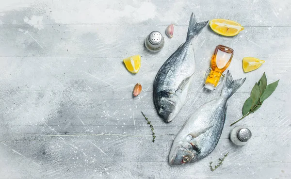 Stock image Raw sea fish with lemon wedges and spices. On a rustic background.