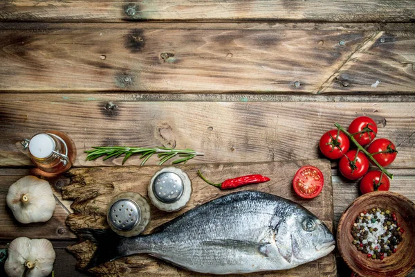 stock image Raw sea fish with tomatoes and herbs. On a wooden background.