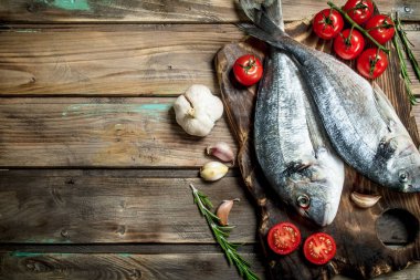 Çiğ deniz domates, baharatlar ve otlar ile dorado balık. Ahşap bir arka plan üzerinde.