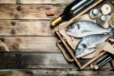 Çiğ deniz balık dorado baharat ve beyaz şarap ile. Ahşap bir arka plan üzerinde.