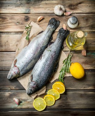 Limon dilimleri ve güzel kokulu biberiye ile eski kağıt üzerinde ham deniz balık somon. Ahşap arka plan üzerinde